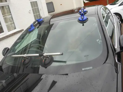 A new windshield held in place with suction cups during fitting